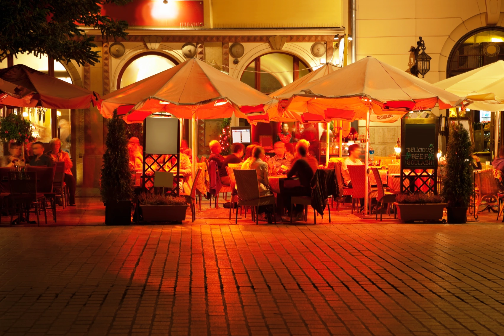 People eat and drink at night at an outdoor café in Kraków, Poland