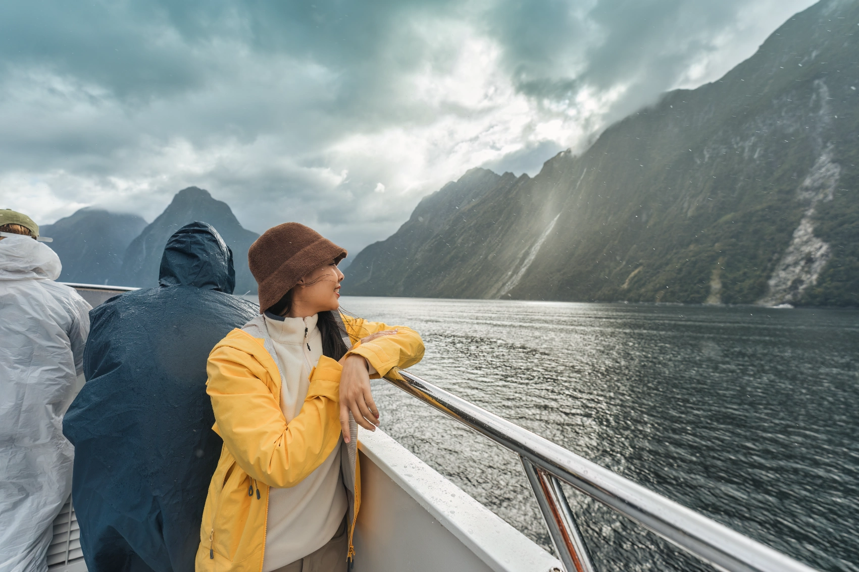 New Zealand rain A woman traveller stands on a cruise boat through Milford Sound, New Zealand, during rainy weather