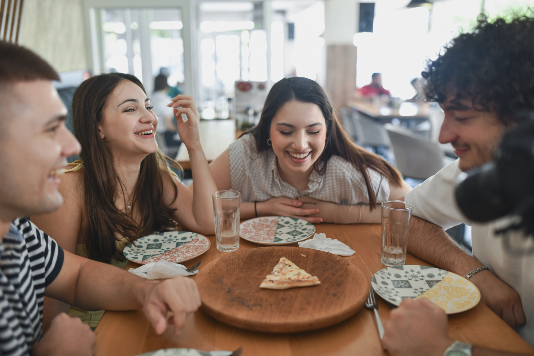 Friends sit around a table in a restaurant looking at a slice of pastrmalija in North Macedonia