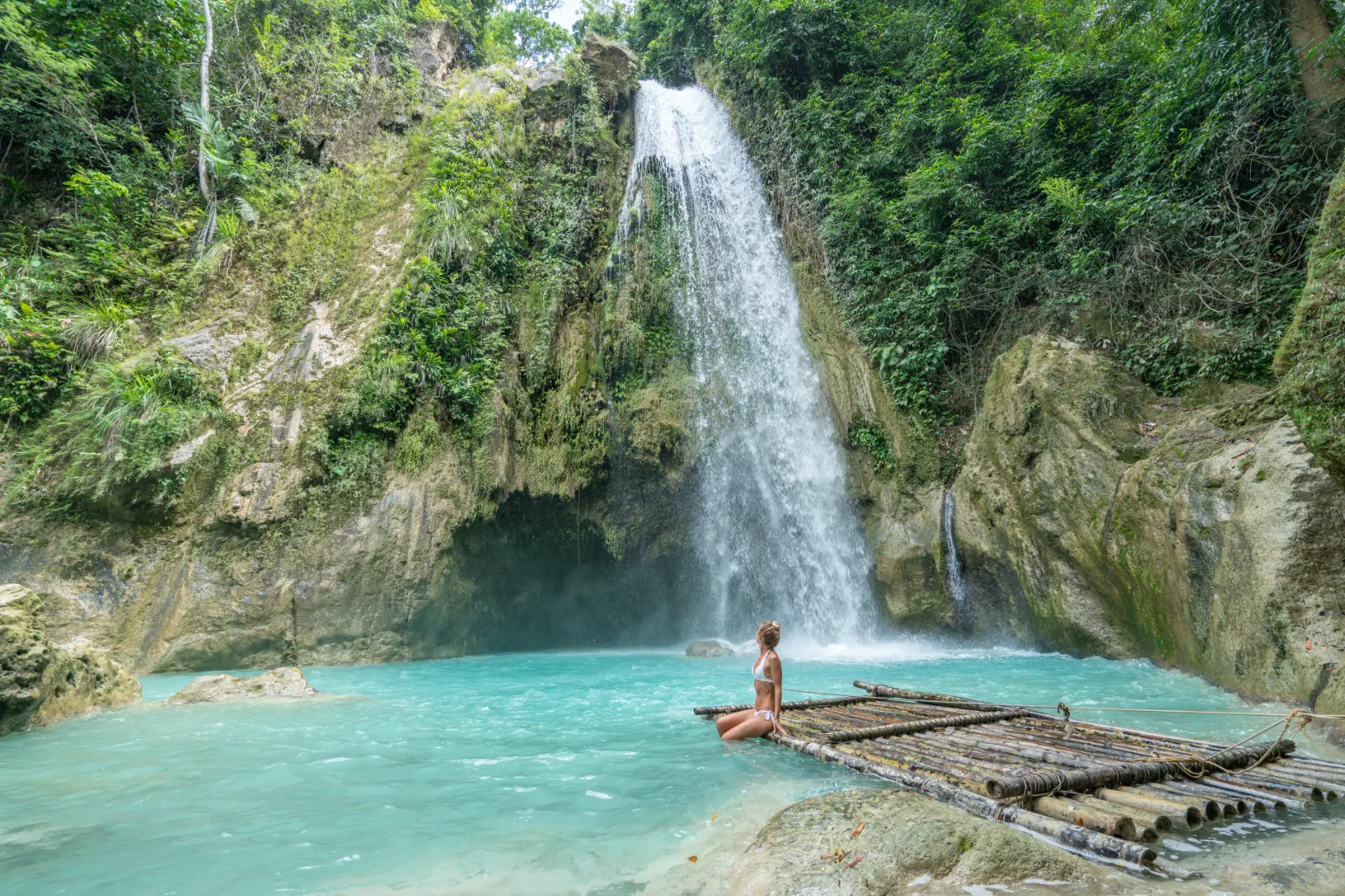 A female traveller sits on a small raft in front of a waterfall on Cebu island, Philippines