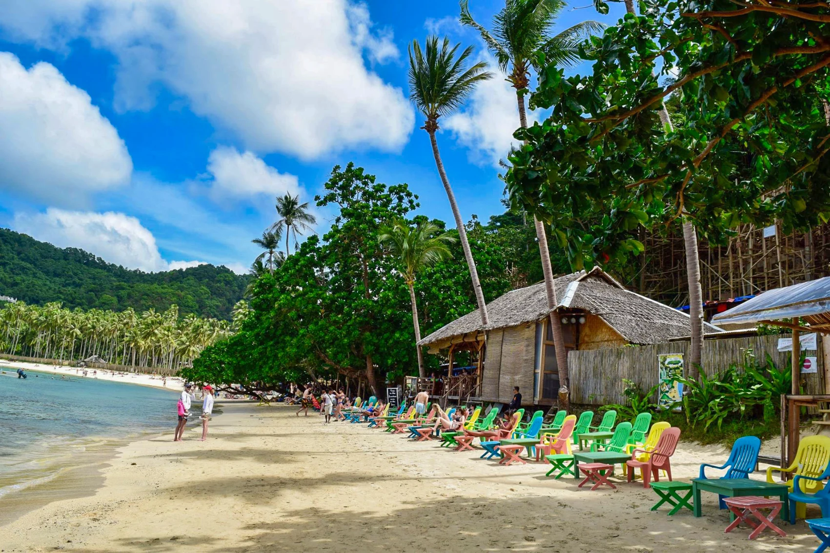 Beach in the Philippines People walk on the beach next to colourful chairs in the Philippines