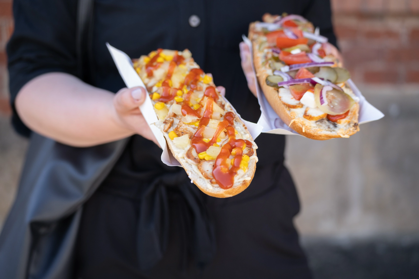 A person holds two open-faced sandwiches called zapiekanka