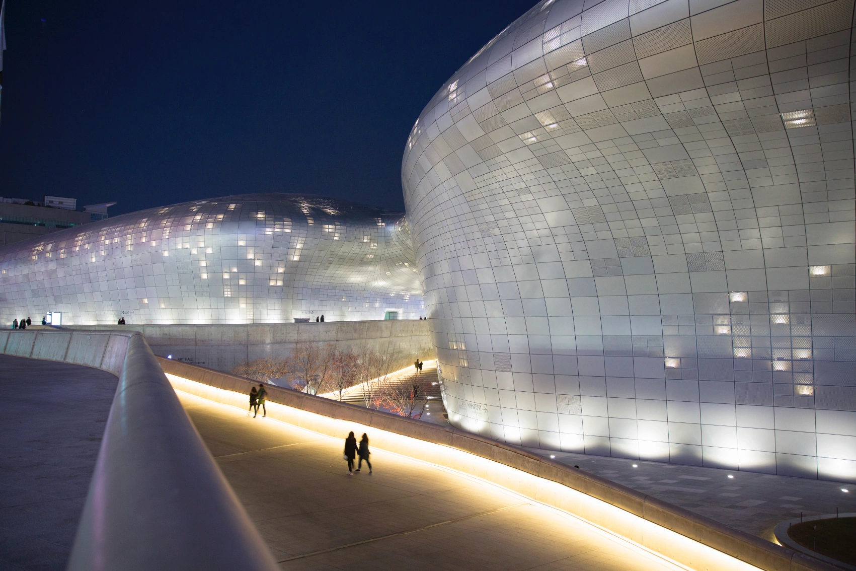 People walking around the Dongdaemun Design Plaza at night in Seoul, South Korea