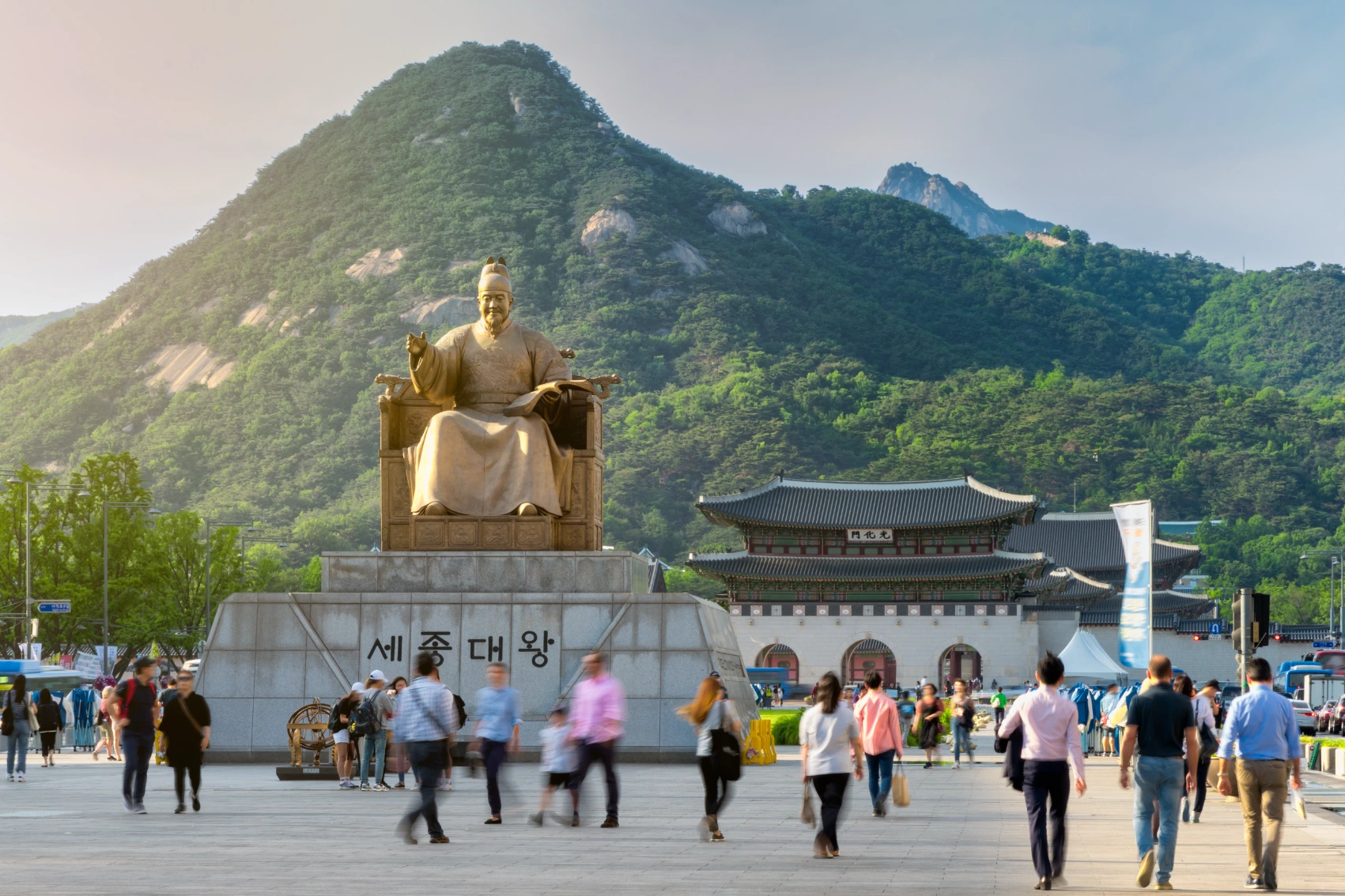 People stroll around the King Sejong Statue in Gwanghwamun Square with the Gwanghwamun Gate in background in Seoul, South Korea