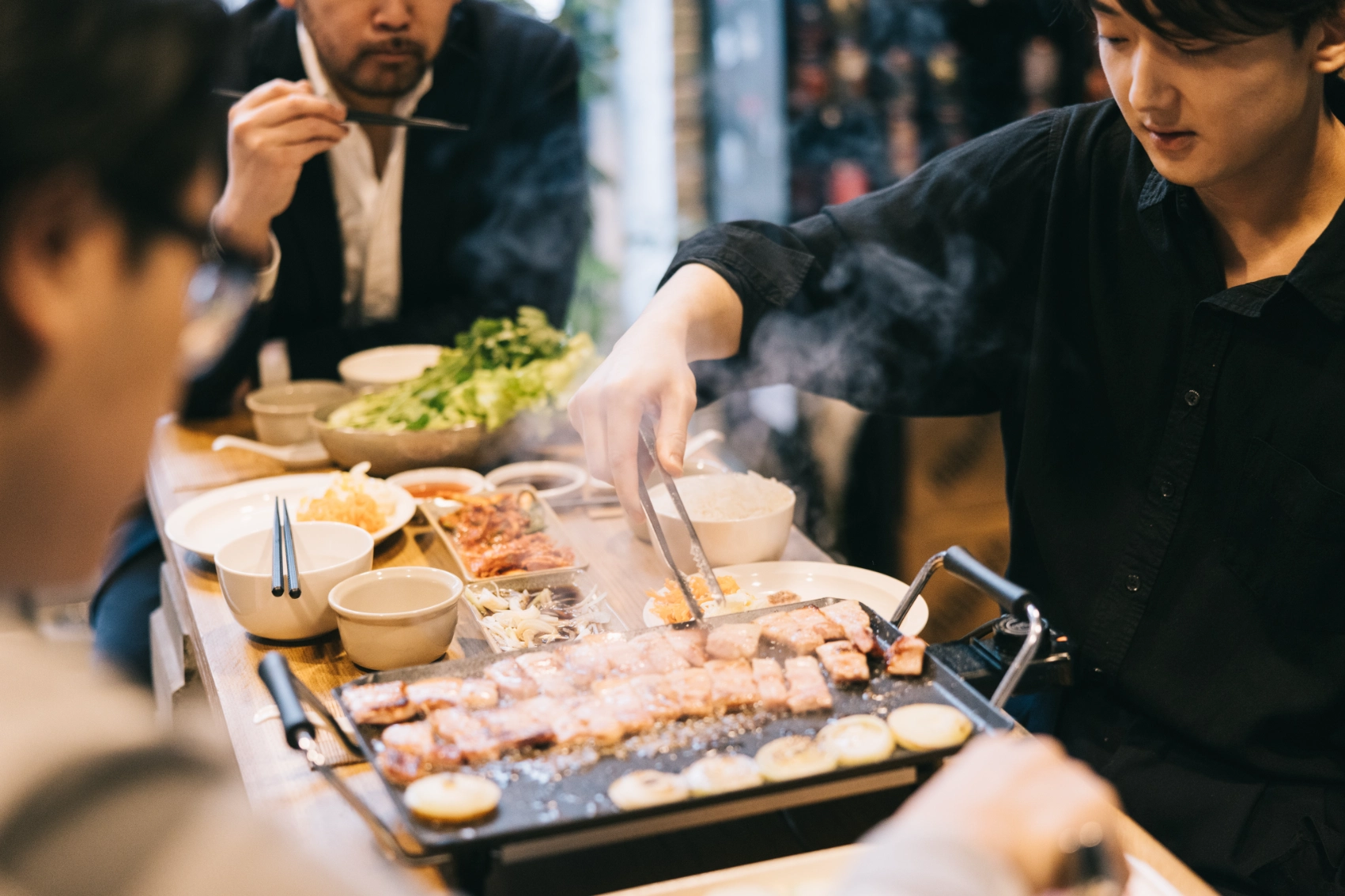 A group of friends sits around a table to grill meat and eat Korean barbecue in South Korea