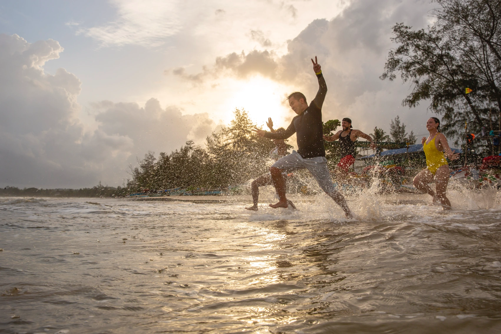 A group of travellers runs into the water from a beach in Sri Lanka