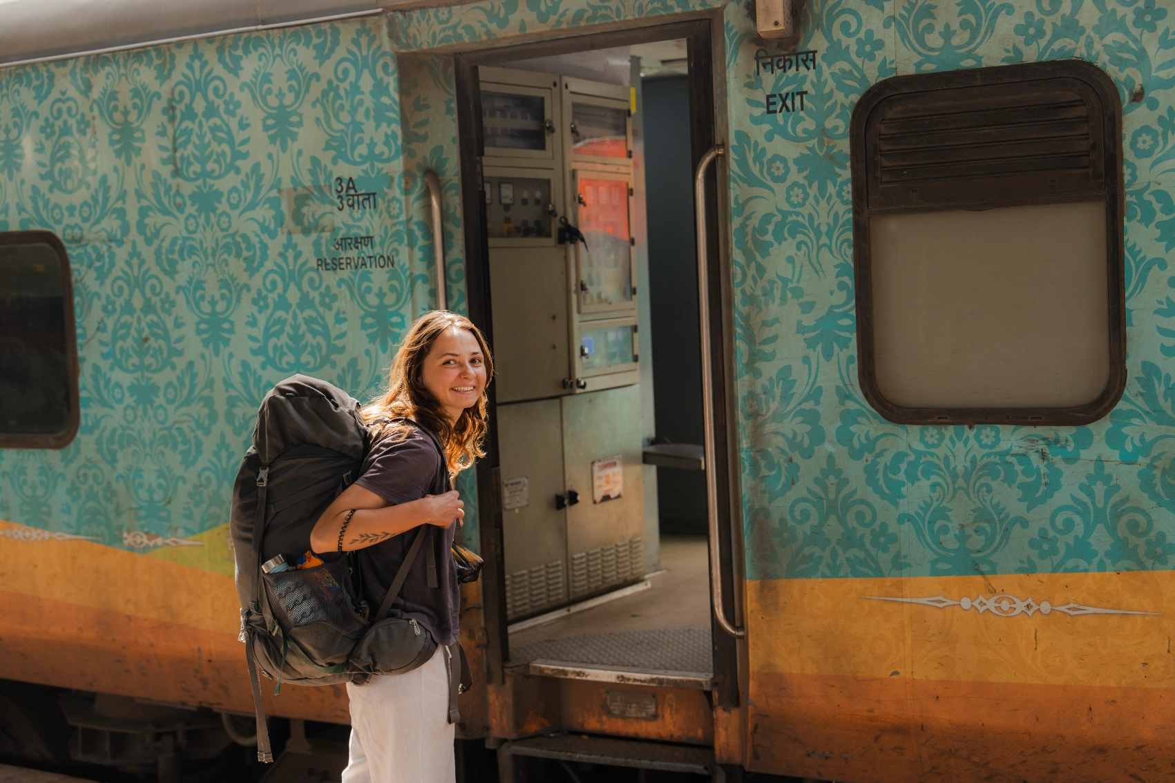A woman traveller with a backpack is ready to get on a train in India