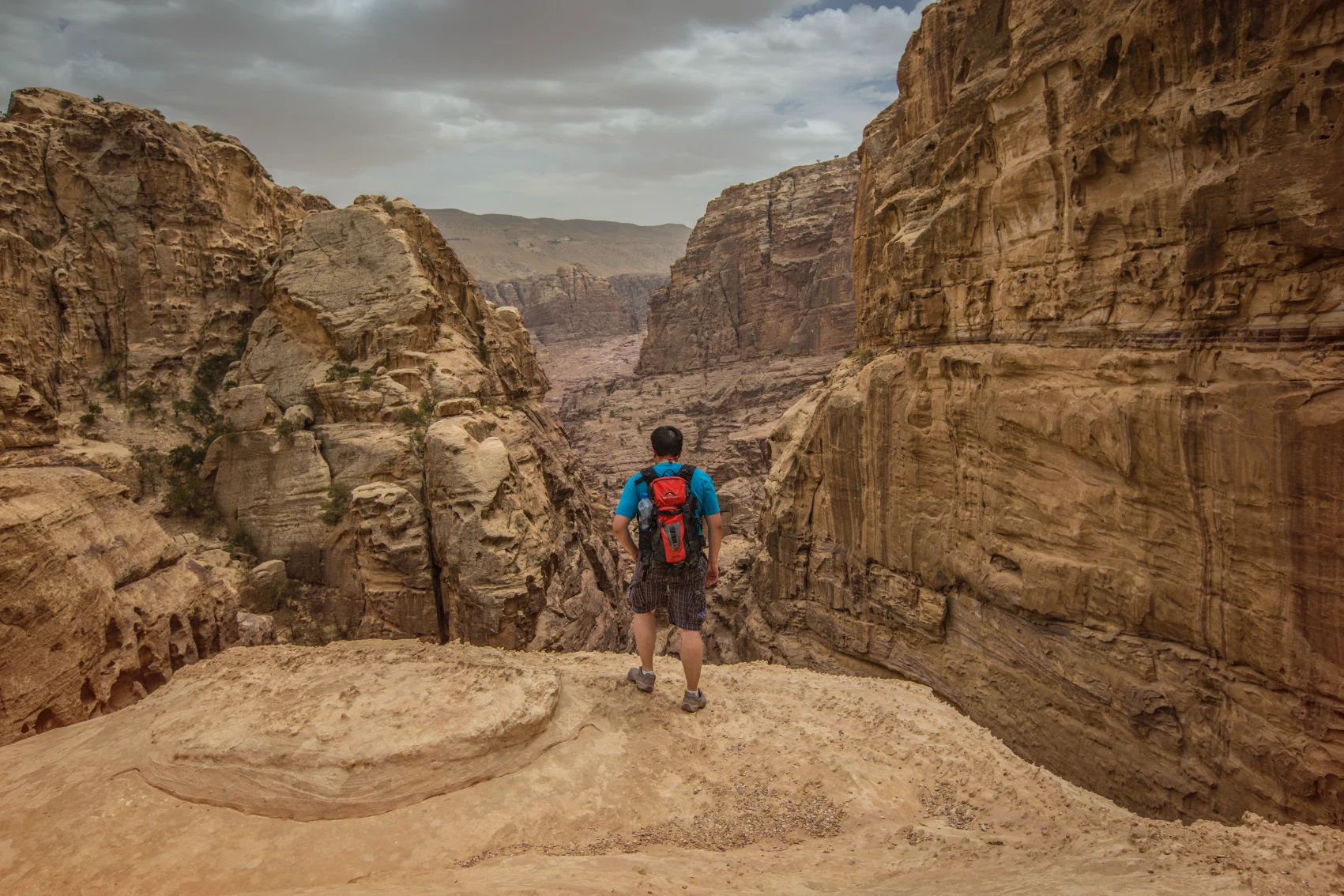 A traveller stands on a rocky outcrop overlooking a canyon in Petra, Jordan
