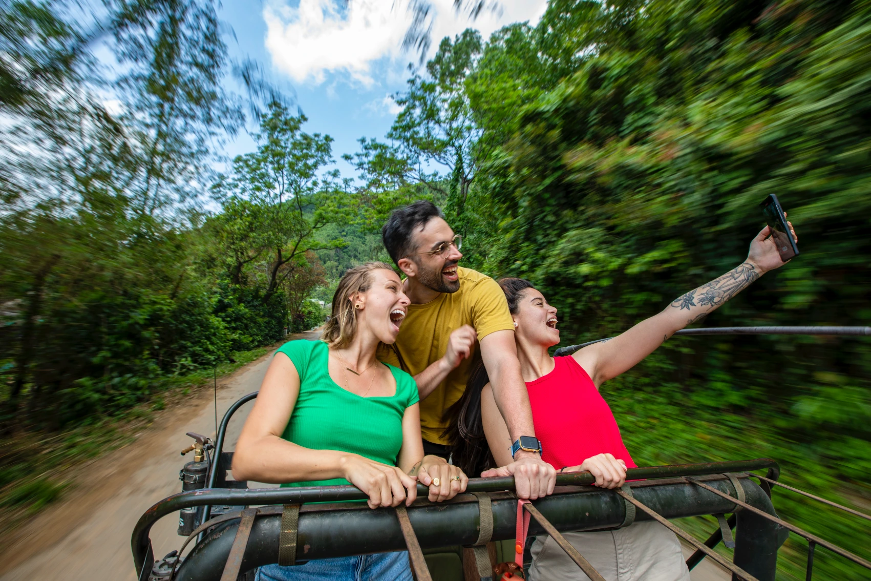 A group of travellers takes a selfie standing in a Jeep in Vietnam