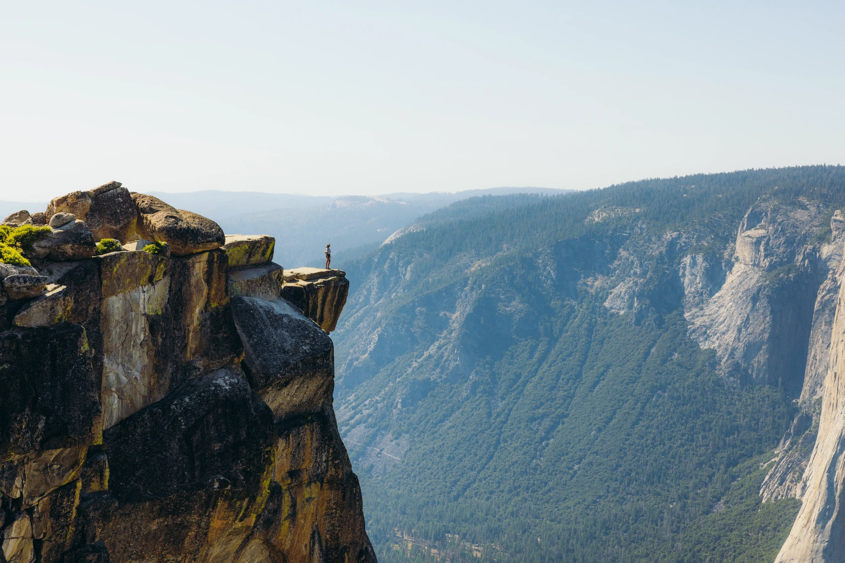 Hiking in Yosemite National Park A hiker stands on a rocky outcrop in Yosemite National Park, California