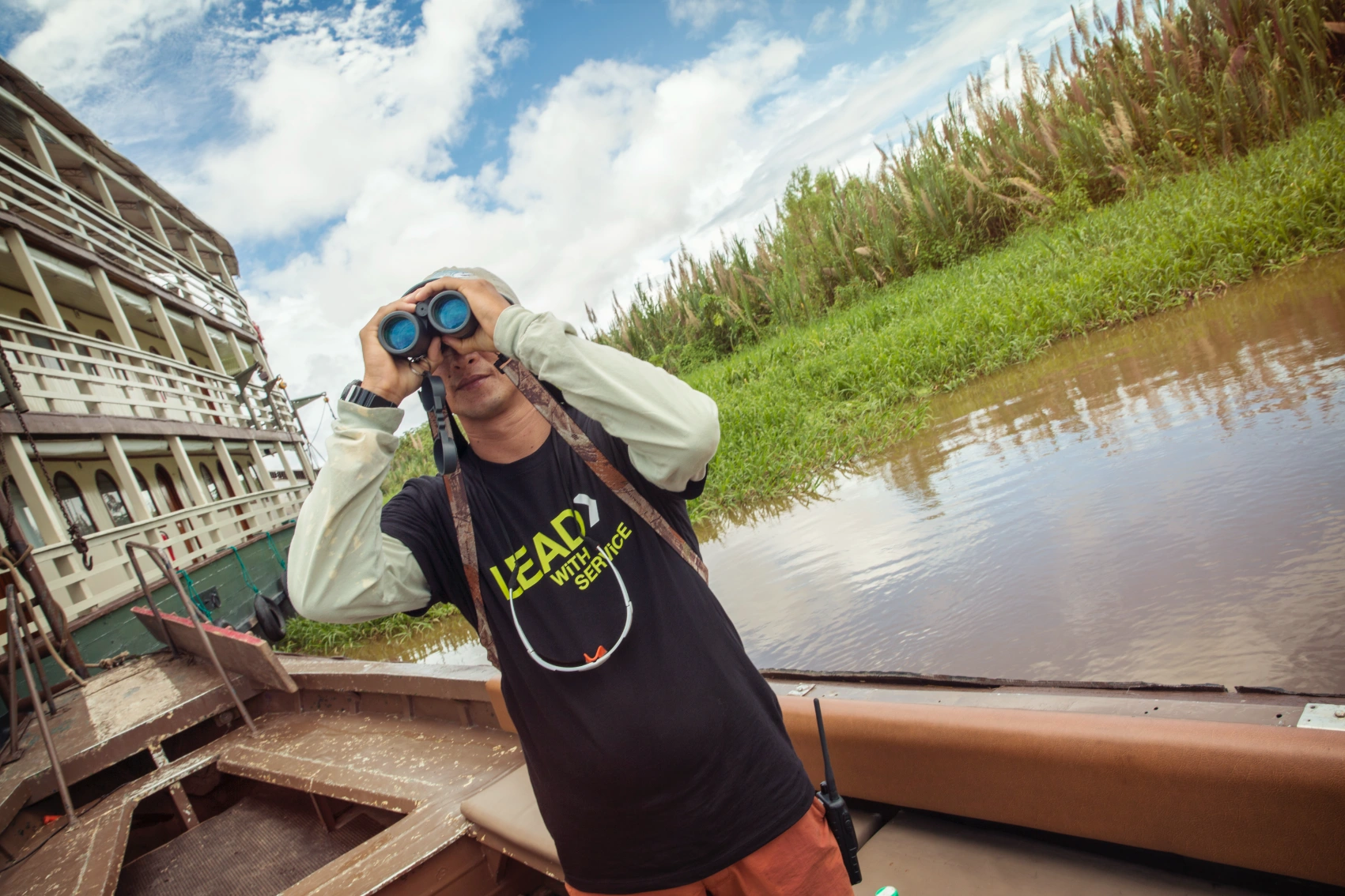 Amazon River, Peru A G Adventures tour leader holds up binoculars while on a houseboat on the Amazon River in Peru