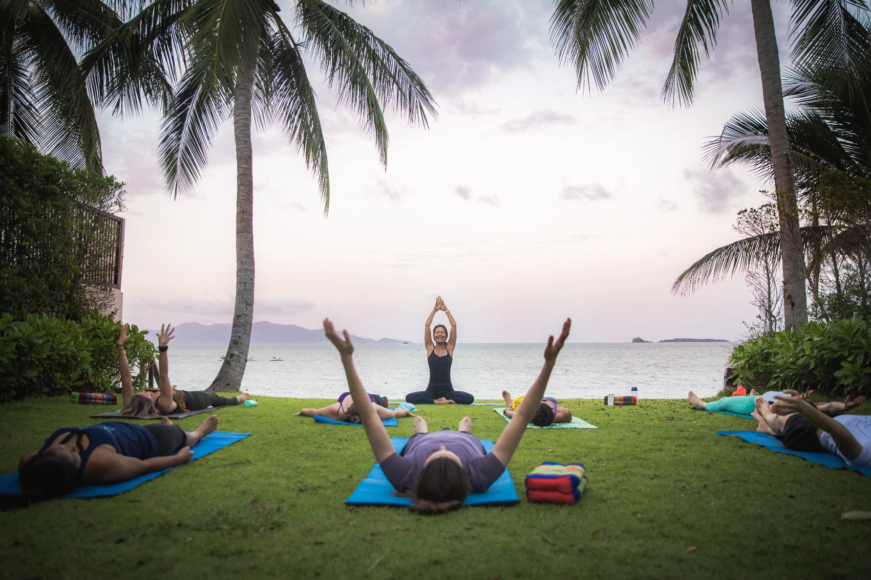 Yoga wellness retreat Travellers in a yoga class surrounded by palm trees with a view of the ocean
