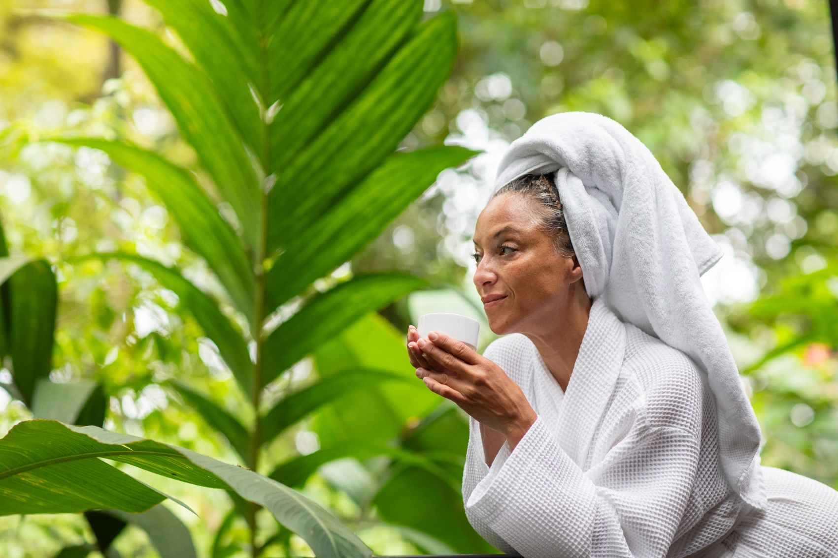 A woman traveller wearing a robe holds a cup of tea in Costa Rica