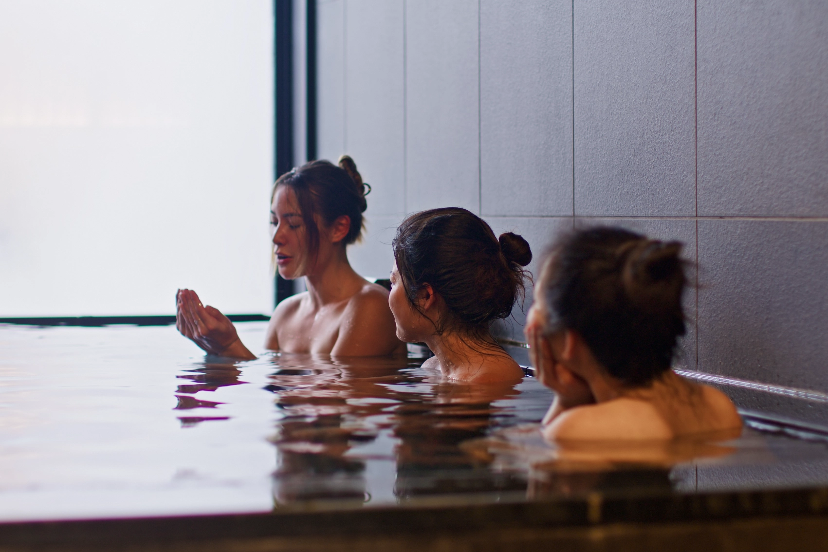 Three women soak in an onsen hot spring in Japan