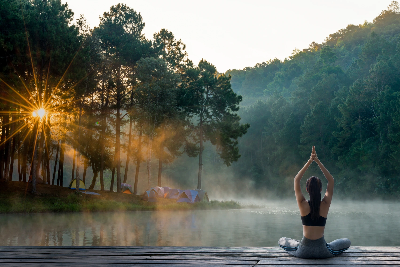 A seated woman lifts her arms in the air in a yoga pose