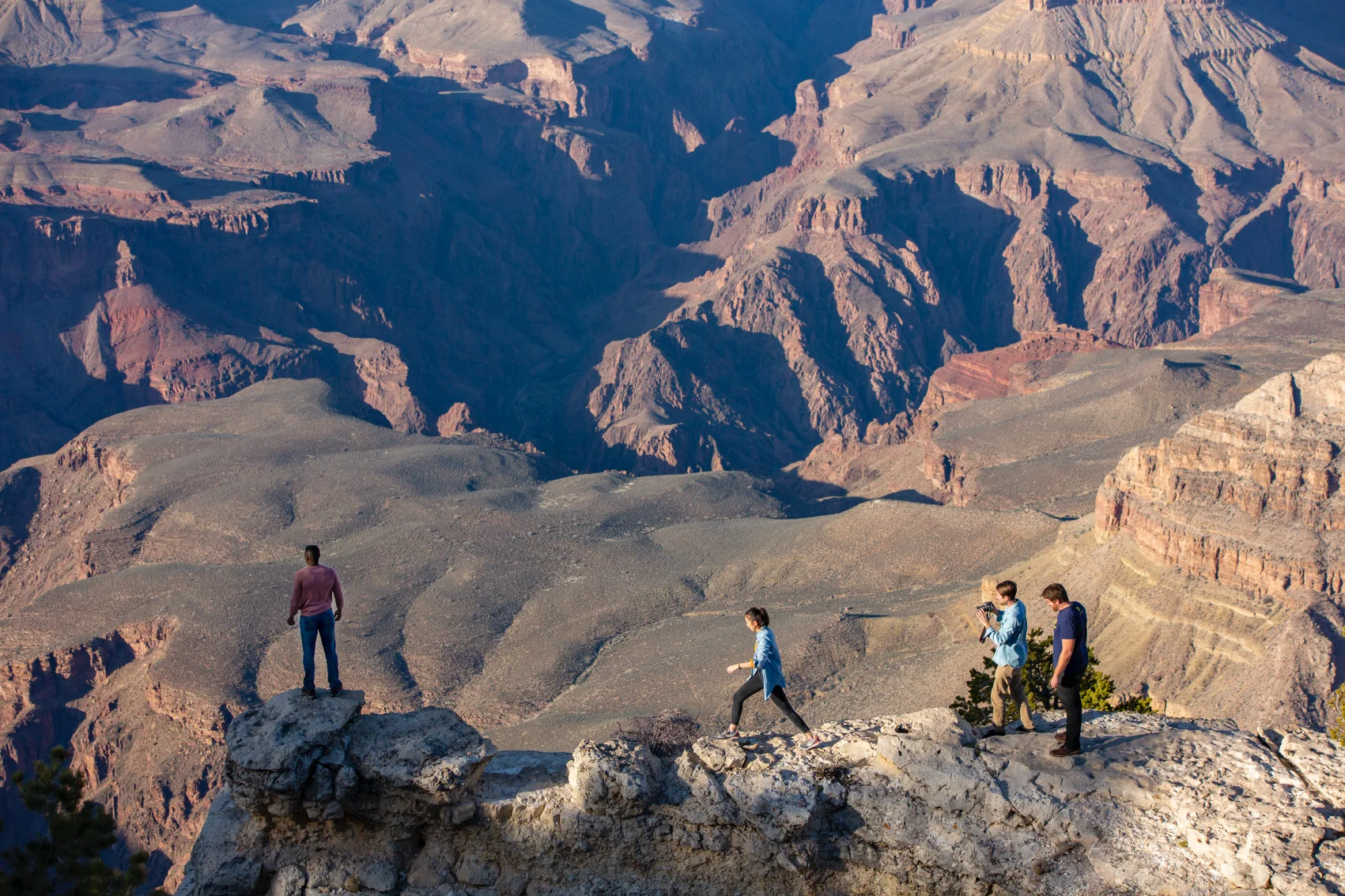 A group of travellers stands on the edge of the Grand Canyon in the United States