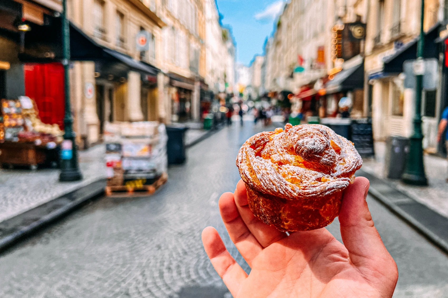 Paris, France A traveller holds up a pastry in a cobblestone street of Paris, France