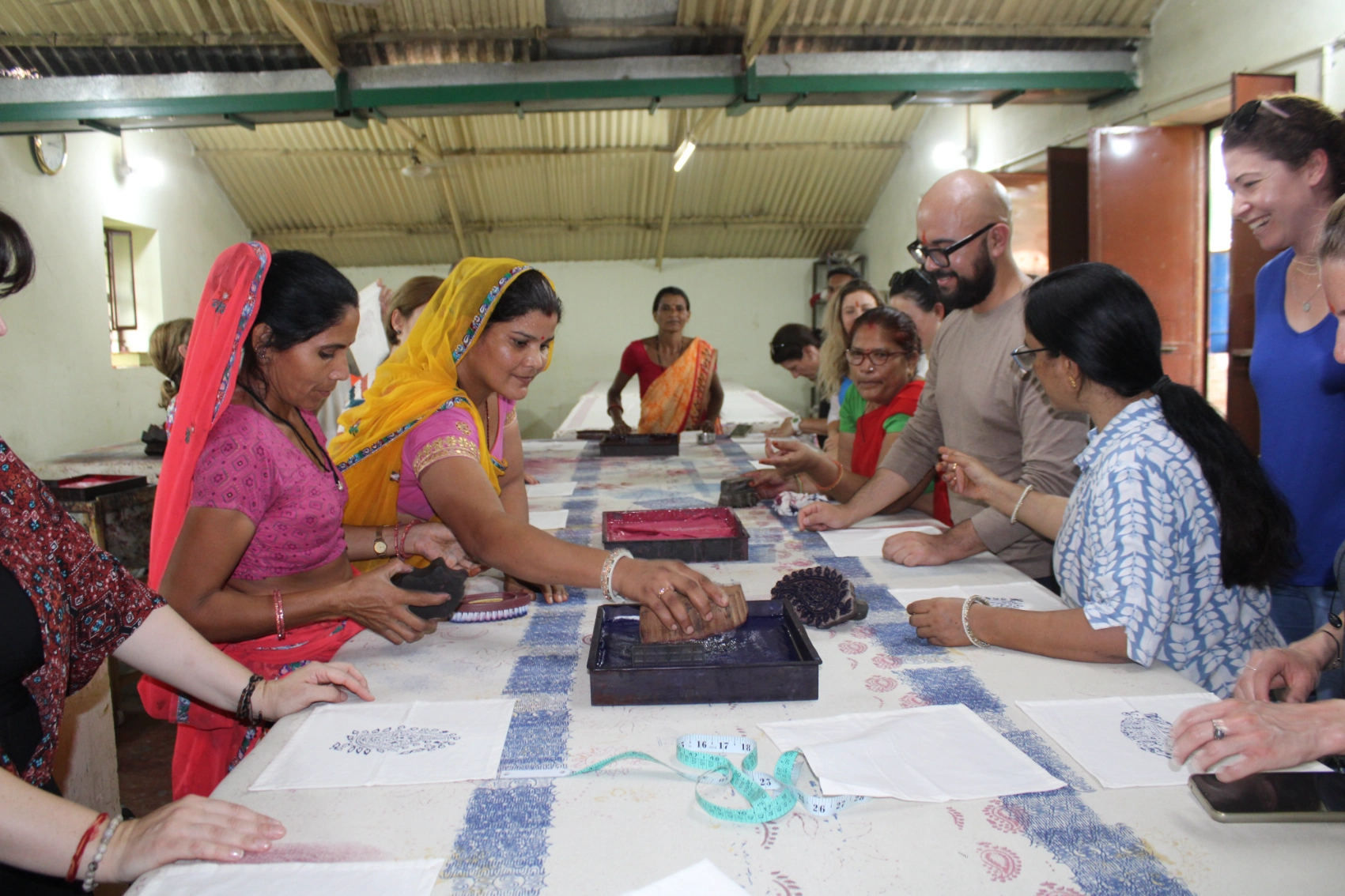 Anoothi India Travellers stand around a table at Anoothi India to watch a woman demonstrating block printing