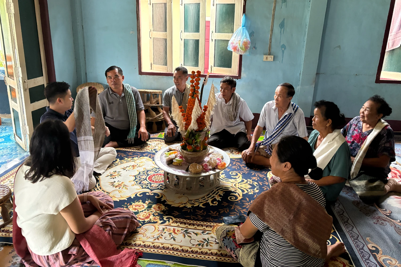 Ban Ou, Laos The staff at Ban Ou Community Tourism in Laos sit in a circle while looking at a scarf