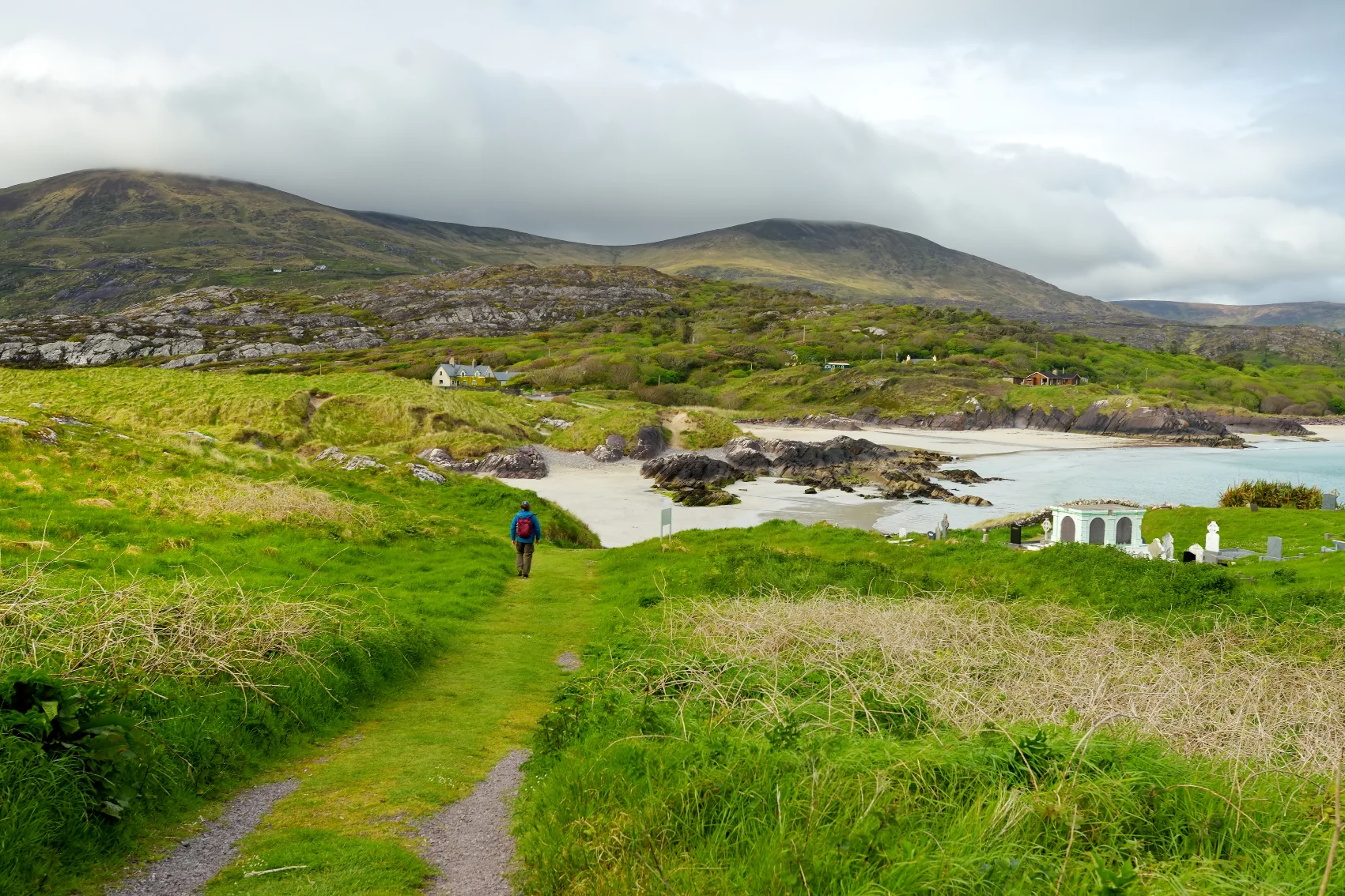 A hiker walks on a trail leading to Derrynane Bay in Ireland
