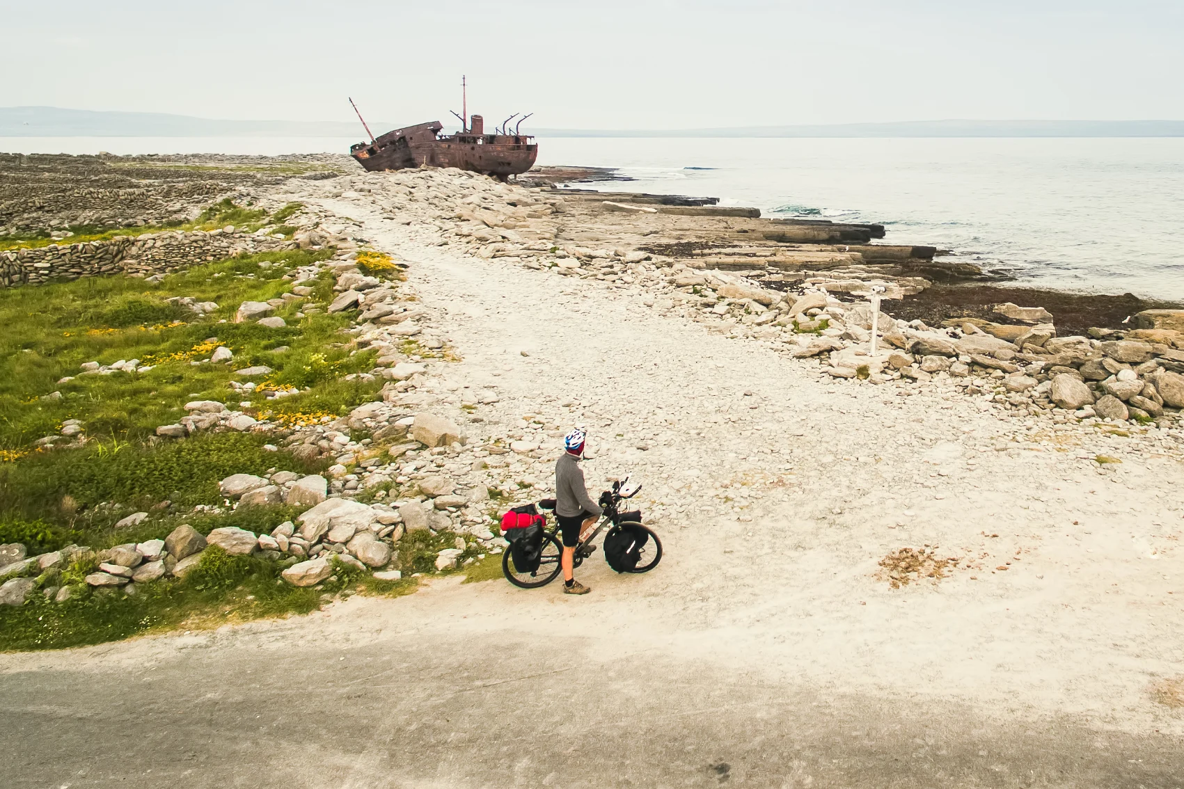 A cyclist pauses near the Plassey shipwreck on Inisheer Island in Ireland