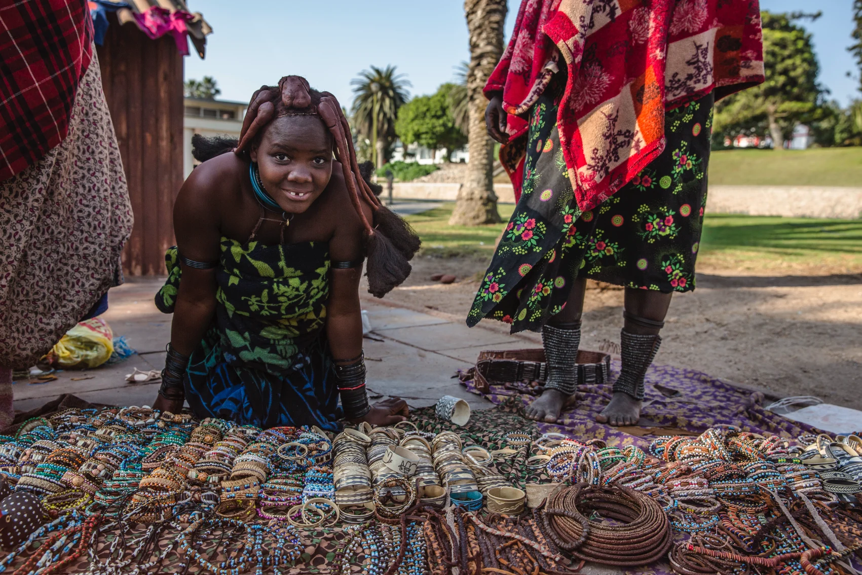A Himba woman sits on a blanket filled with jewellery in Namibia