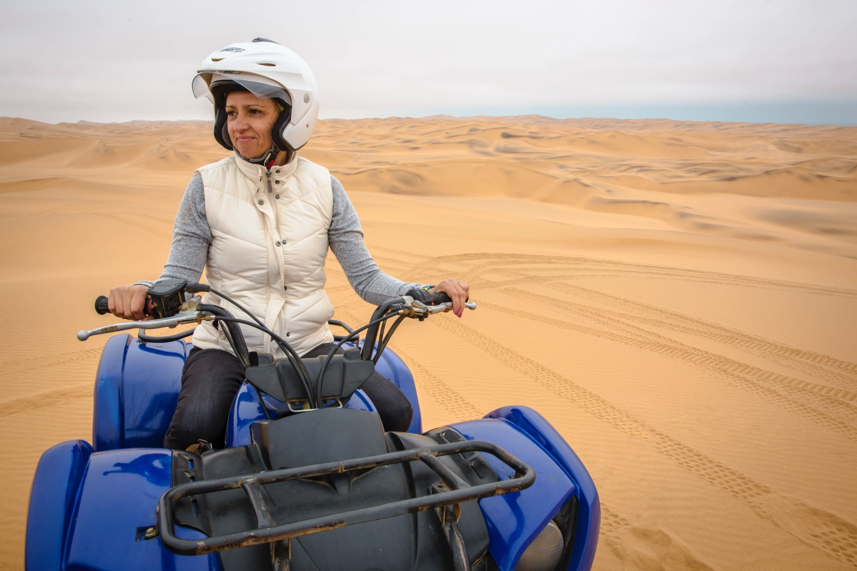 A woman traveller sits on a quad bike in the dunes around Swakopmund, Namibia