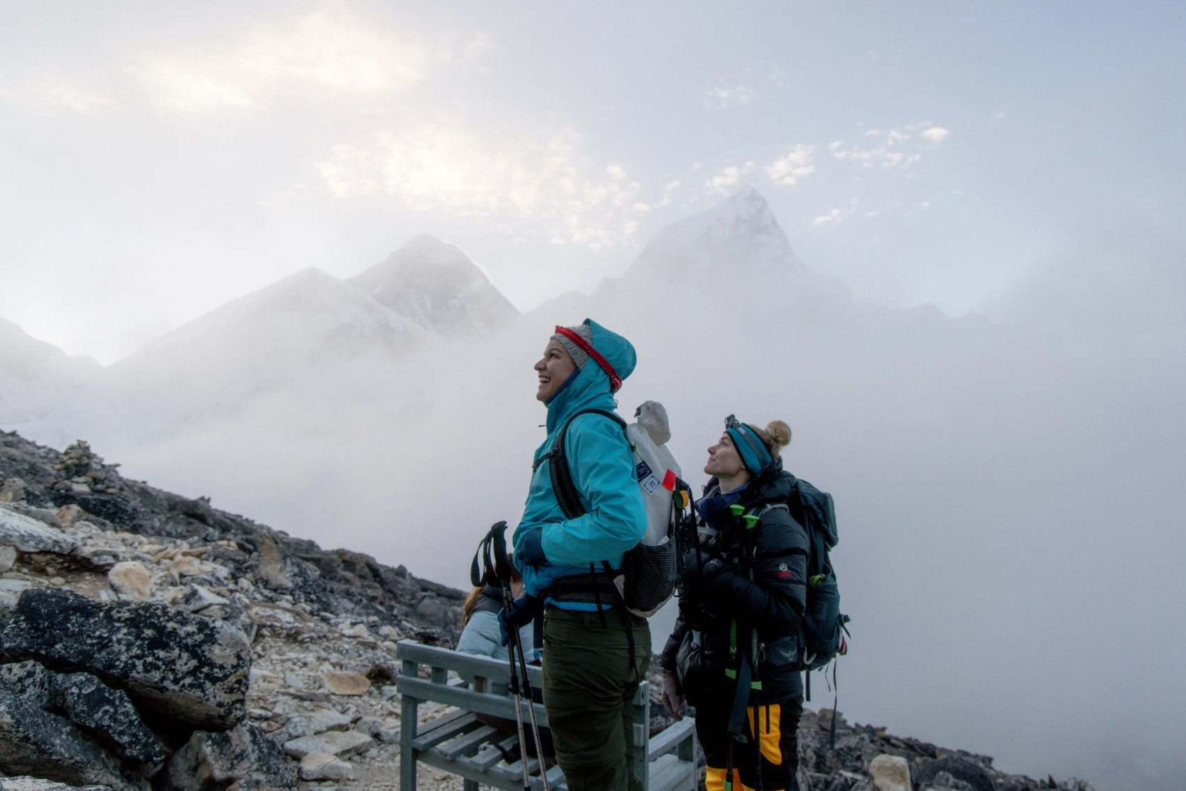 A group of hikers in large coats treks through snowy mountains in Nepal