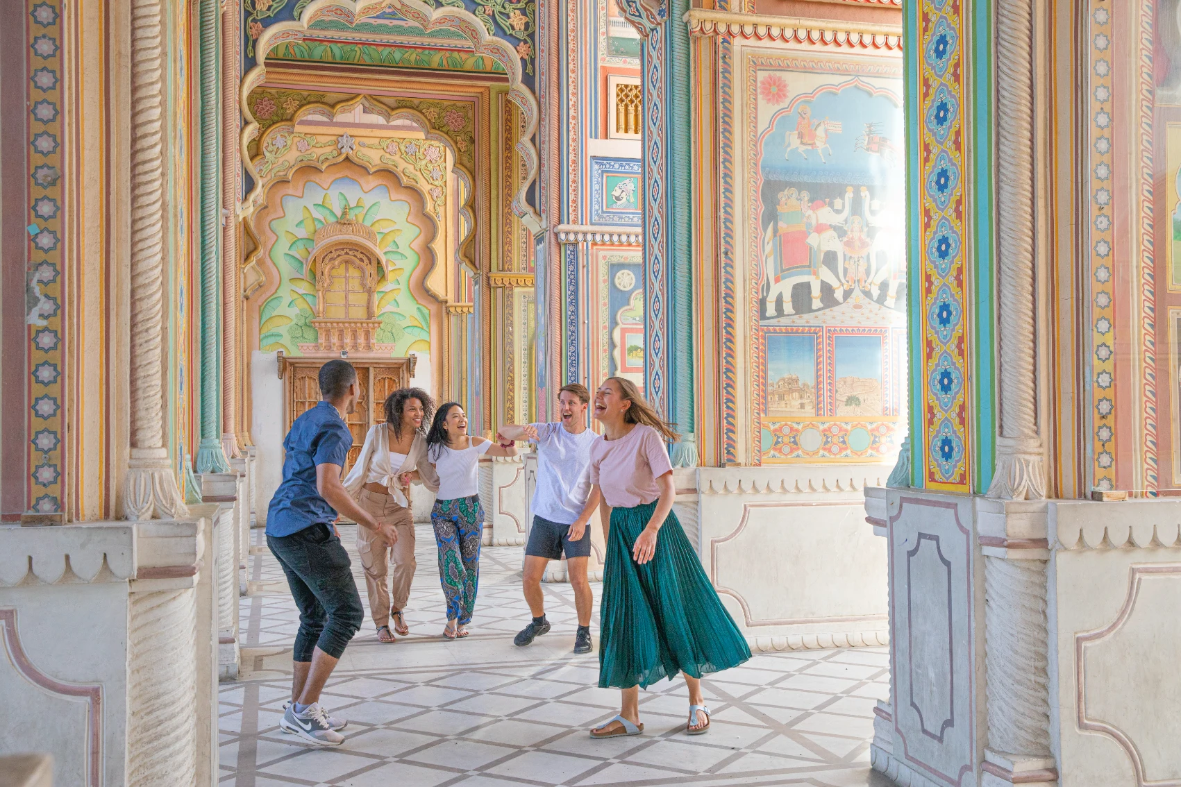 A group of travellers walks through the colourfully painted Patrika Gate in Jaipur, India