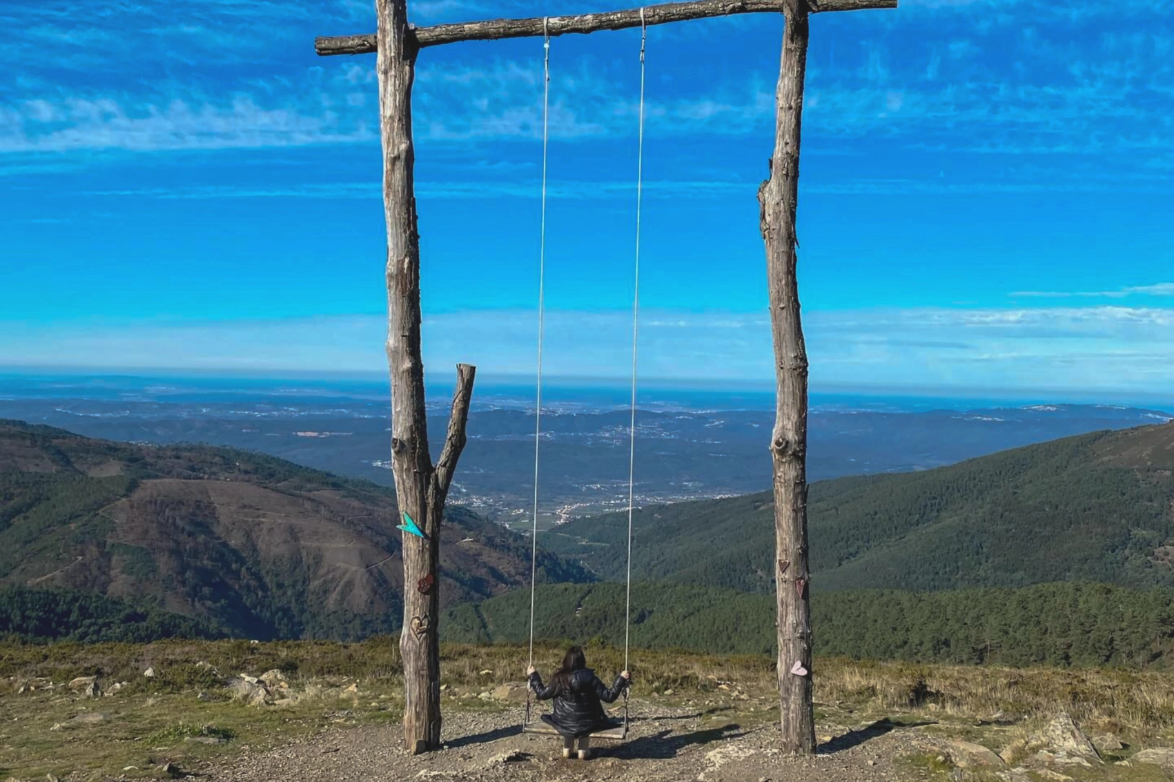 A woman traveller on a swing looks out at the landscape of central Portugal