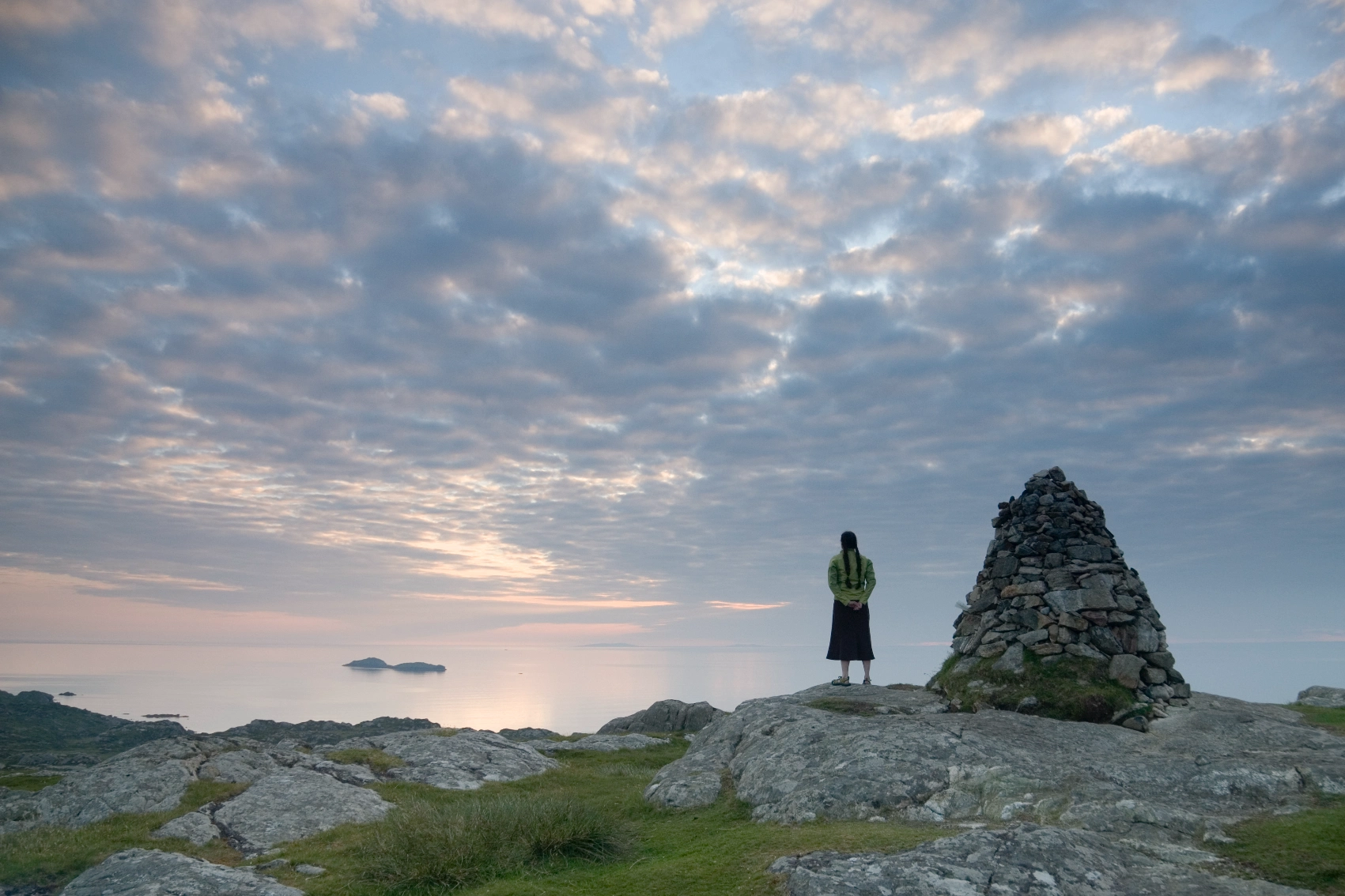 Iona, Scottish Isles A traveller looking out from rocky Iona, a Scottish Isle, to the ocean with a dramatic sky overhead
