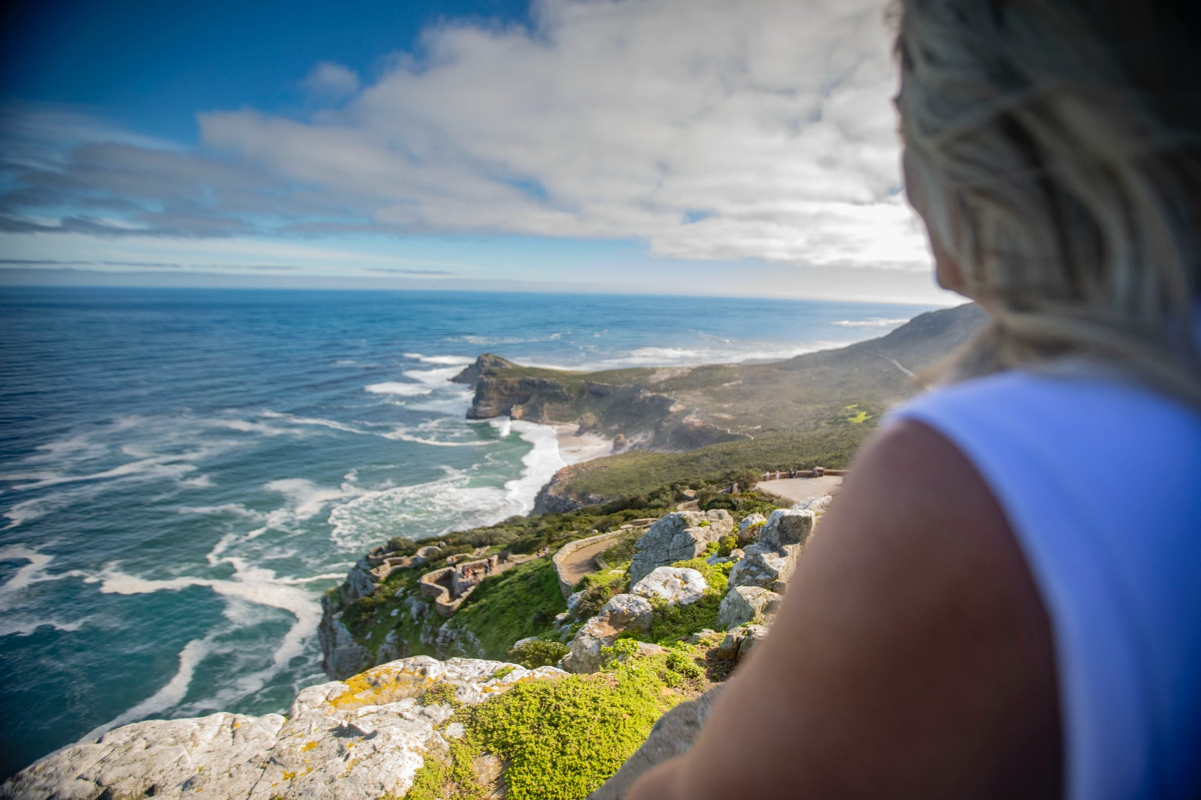 A woman traveller looks out at the ocean from a viewpoint in South Africa