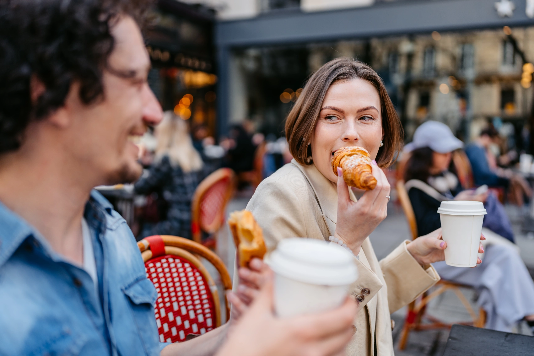 Two people eat croissants at a sidewalk café in Paris