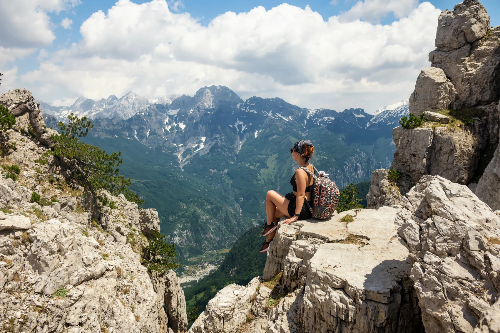 A woman traveller sits on a rock overlooking the Accursed Mountains in Albania