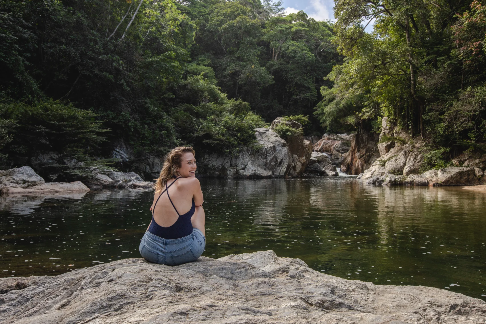 A woman traveller sits near a jungle-surrounded lake in Tayrona National Park, Colombia