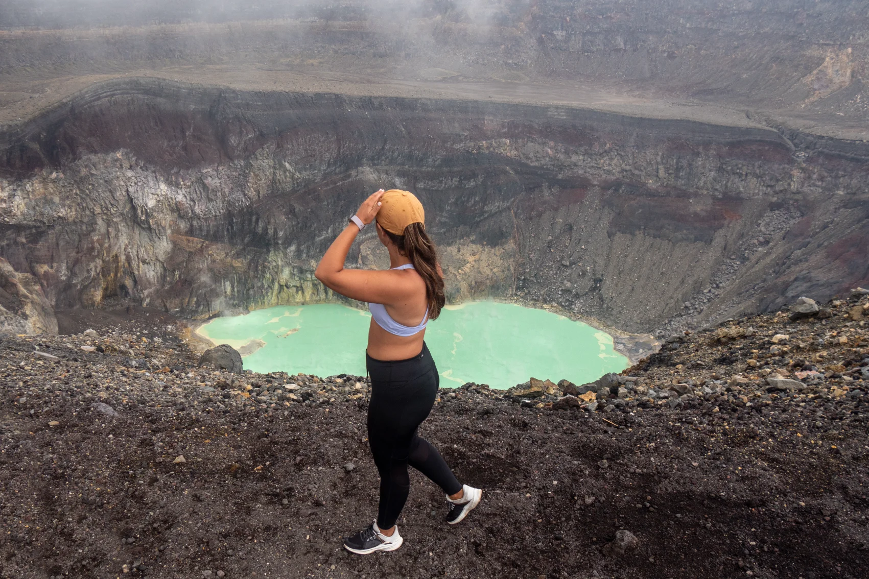 A woman traveller hikes along the edge of a volcano crater in El Salvador