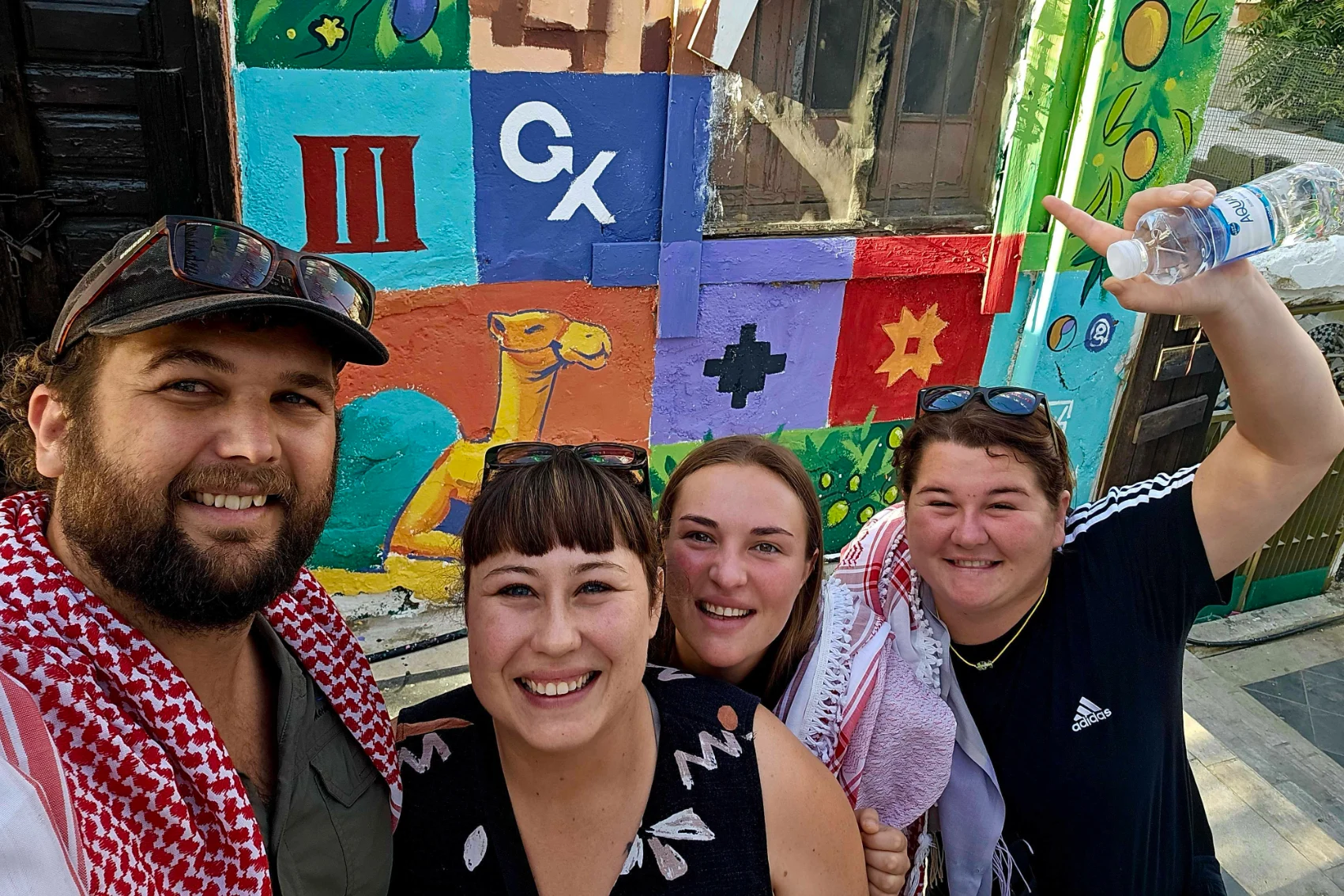 A group of people stands in front of a mural painted for World Tourism Day 2025 in Amman, Jordan