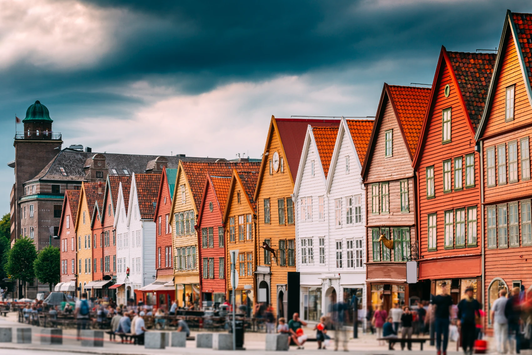 People walk in front of colourful buildings in Bryggen Wharf in Bergen, Norway