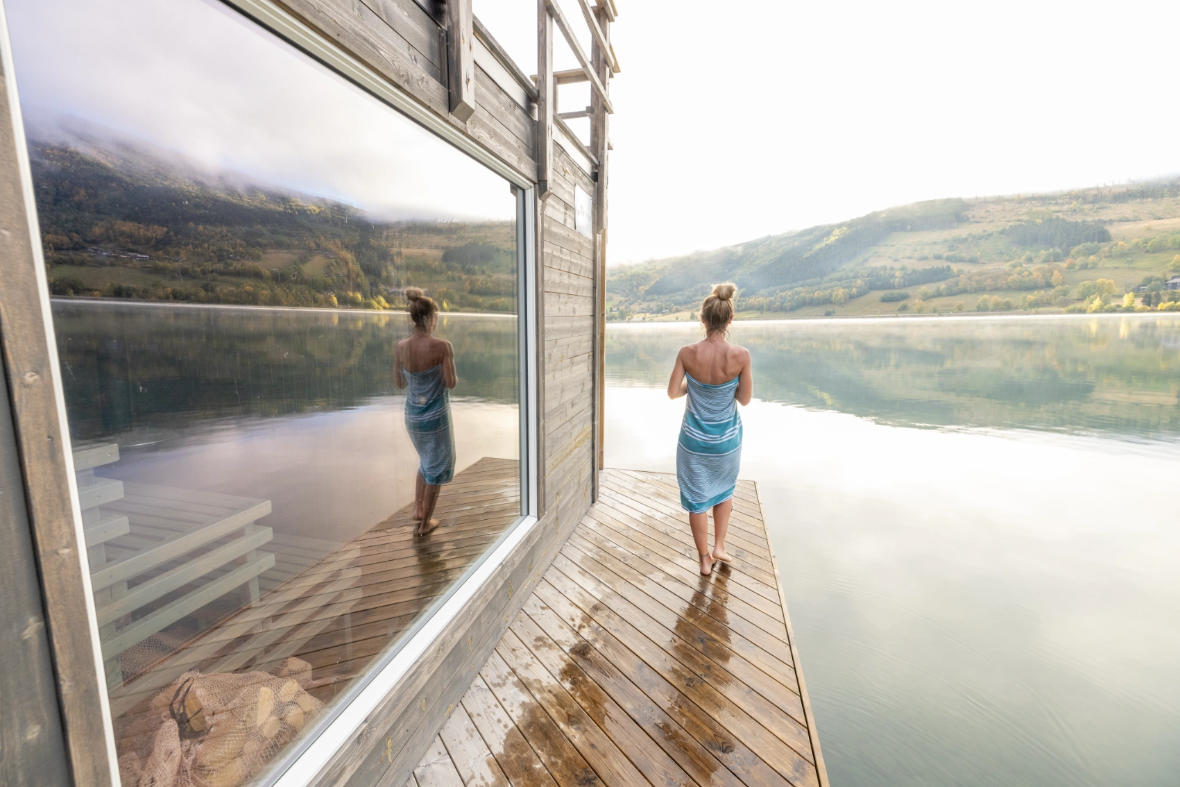 A woman traveller walks along a wooden walkway at a floating sauna in Norway
