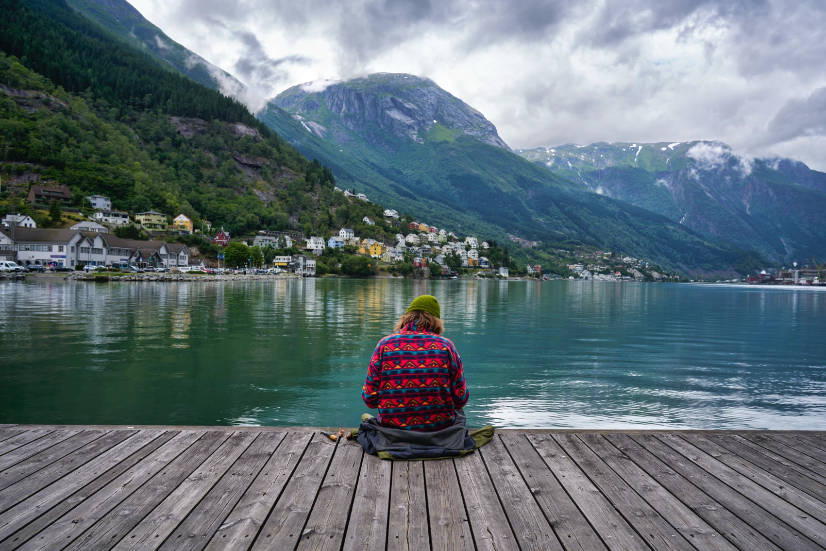 A solo traveller sits on a dock overlooking fjords in Bergen, Norway