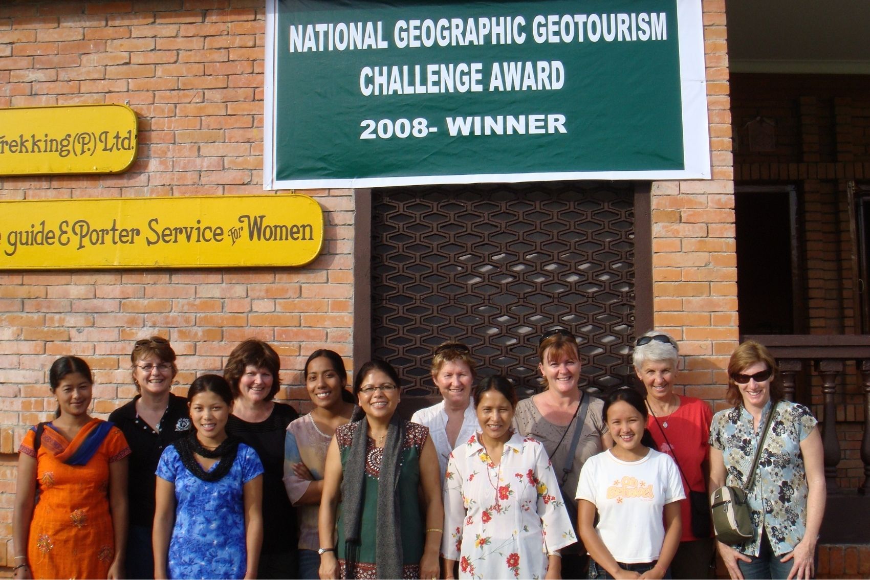 The three sisters trekking guides standing in front of a sign in with a group of travellers