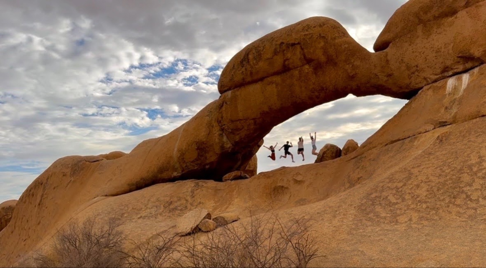 Swiss traveller Michelle Meyer and a group of travellers jumping under an arch on a G Adventures