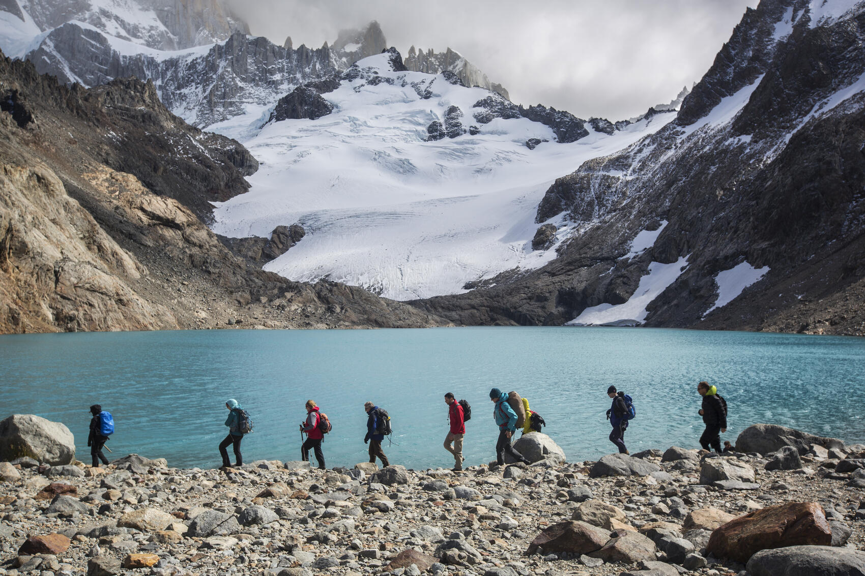 A group of travellers hiking in front of mountains and a lake in Patagonia