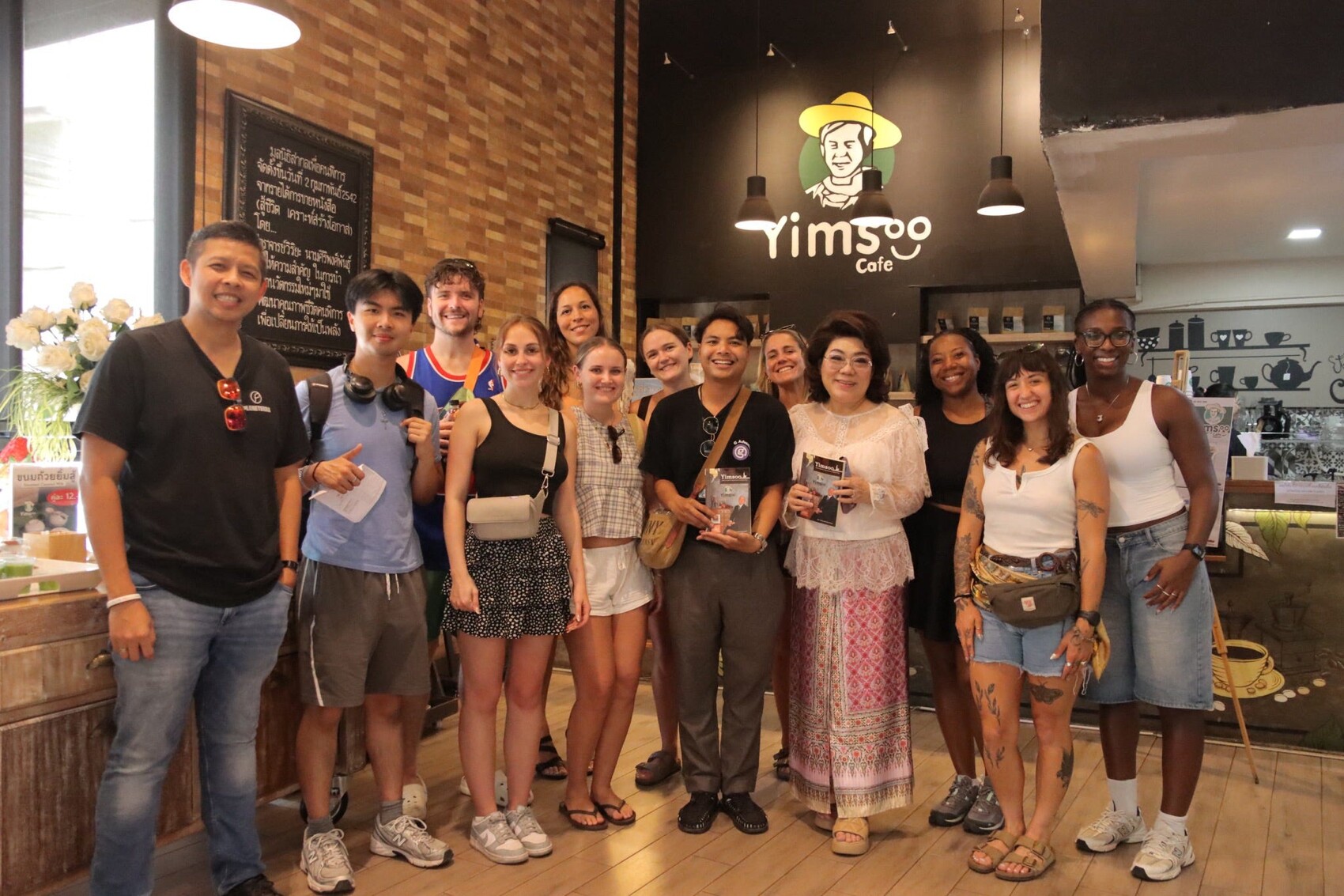 CEO Sonny Prarohittanont and a group of travellers posing for a photograph at Yimsoo Cafe in Thailand