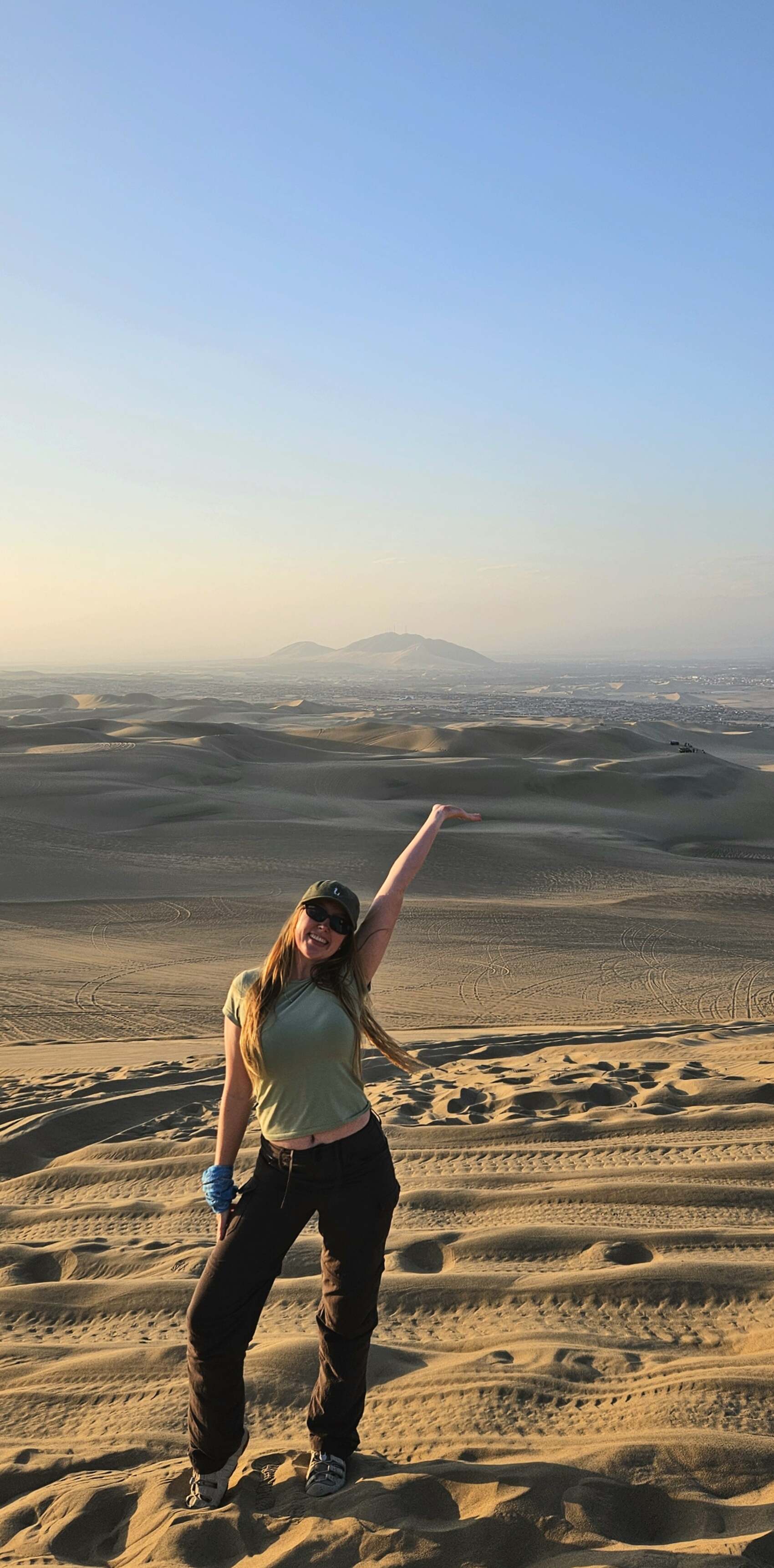 Traveller Milly from New Zealand posing in front of sand dunes in Peru