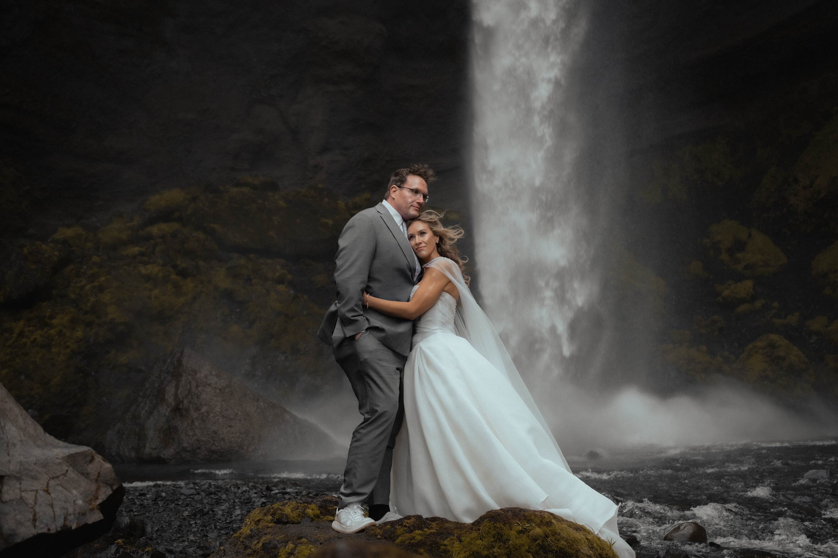 The happy couple on their wedding day by a waterfall in Iceland