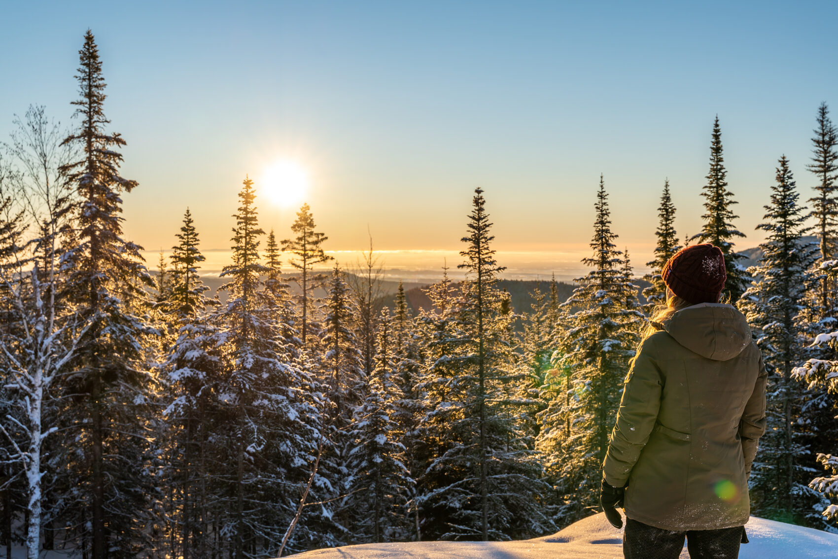 A woman watching the sunrise over a Canadian forest