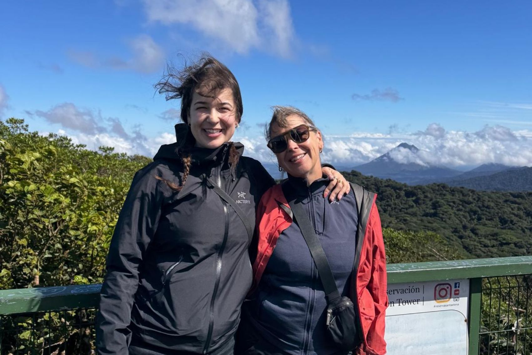 Debbie Bowman and her daughter Amanda posing for a photo in front of jungle-covered volcanoes in Costa Rica