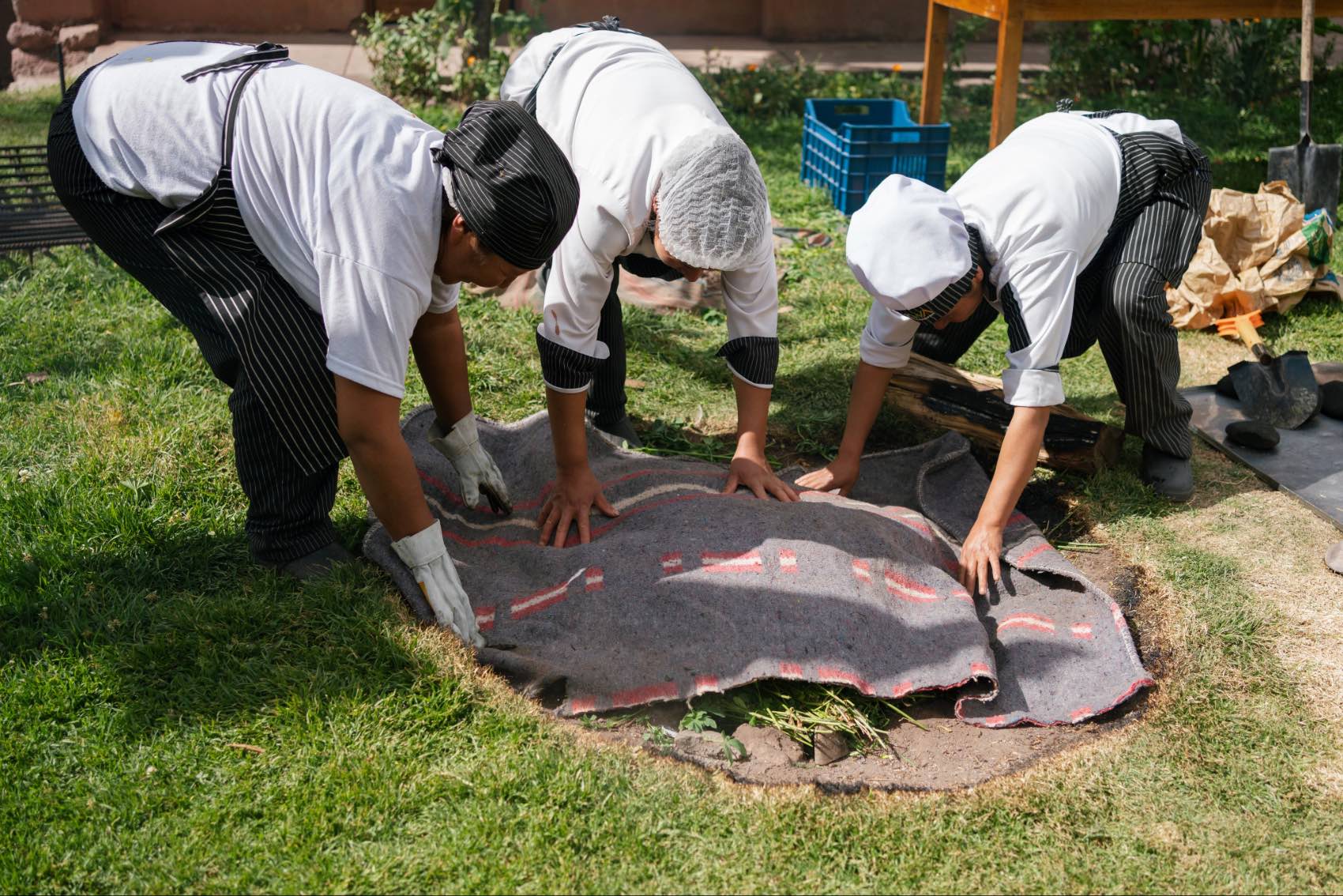 Women at Peru’s Parwa Community Restaurant preparing an earth oven for pachamanca