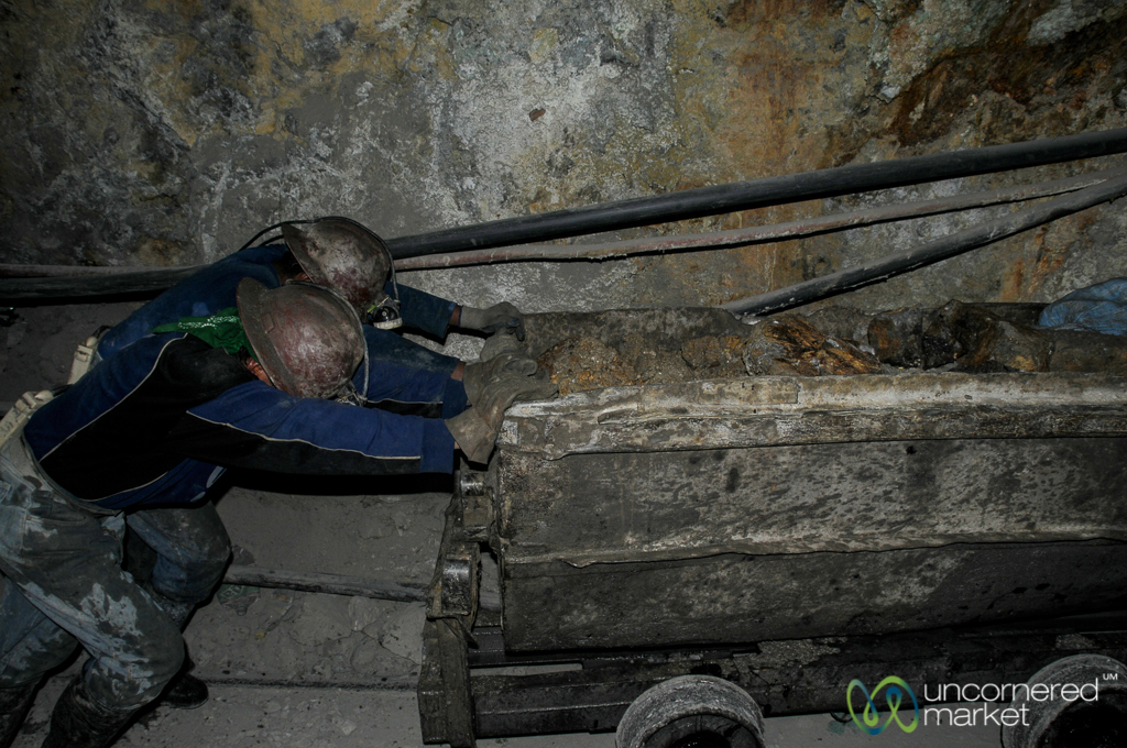 Pushing wagons filled with rock and rubble out of the mines. The materials then go to a processing centre where chemicals extract minerals.